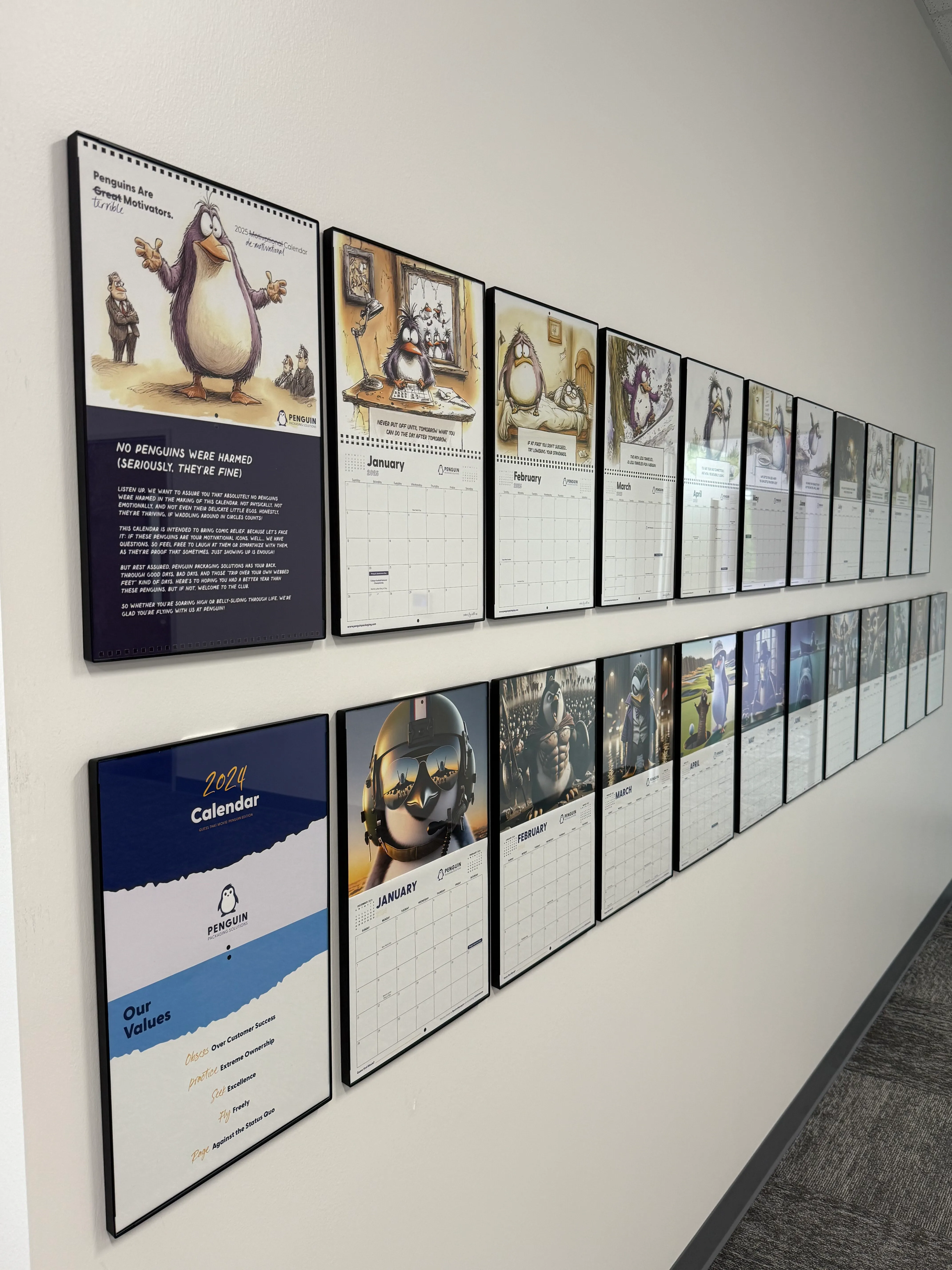 Two years of illustrated Penguin calendars displayed in the office